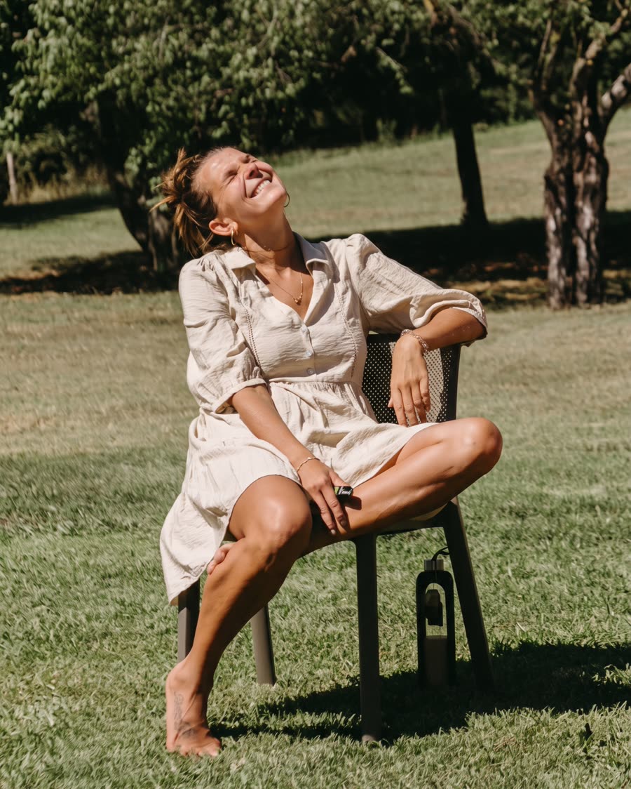 A participant laughing in the sun, sitting on a chair on the lawn