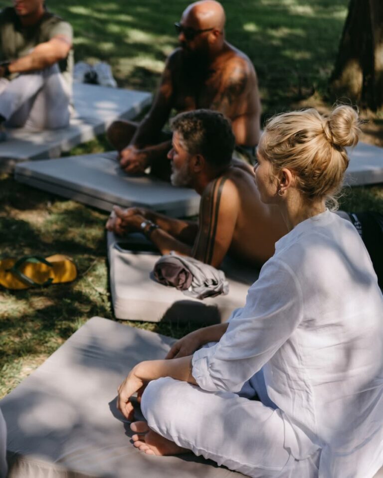 Participants sitting quietly on mats in the shade of the garden