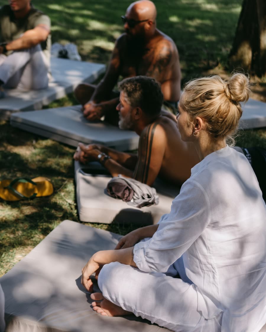 Participants sitting quietly on mats in the shade of the garden